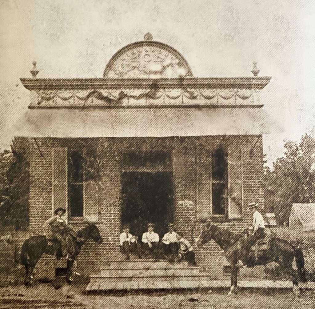 Old sepiatone photograph of WSB's historic first building and men on horseback.
